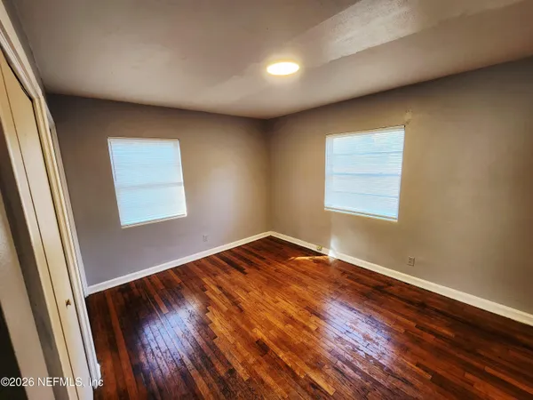an empty room with wooden floor and windows