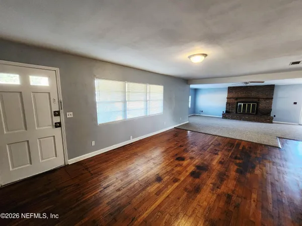 an empty room with wooden floor and windows