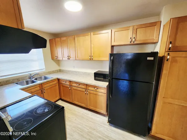 a kitchen with stainless steel appliances a refrigerator a sink and wooden cabinets