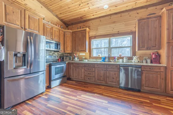 a kitchen with granite countertop stainless steel appliances a sink a window and cabinets