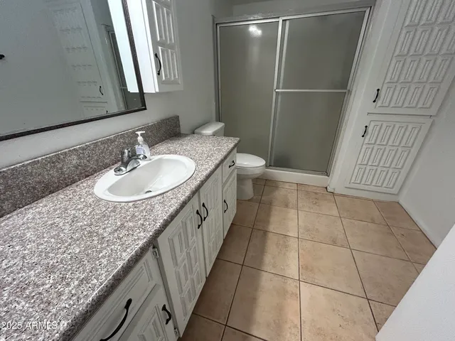 a bathroom with a granite countertop sink a mirror and shower