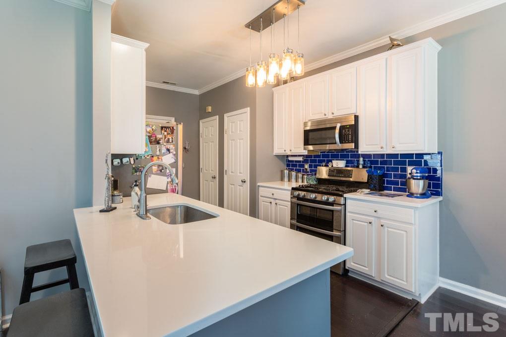 8419 Tie Stone Way Raleigh, NC 27613 - Photo 3 of 30 a kitchen with kitchen island a sink stove and microwave