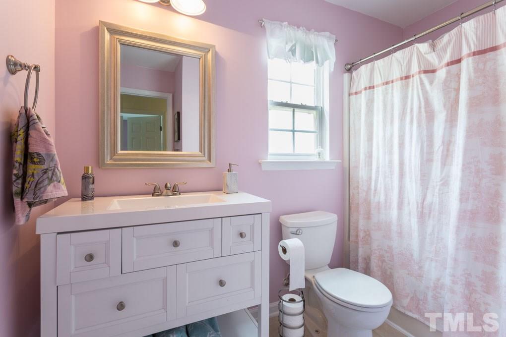 8419 Tie Stone Way Raleigh, NC 27613 - Photo 23 of 30 a bathroom with a granite countertop sink a toilet and a mirror