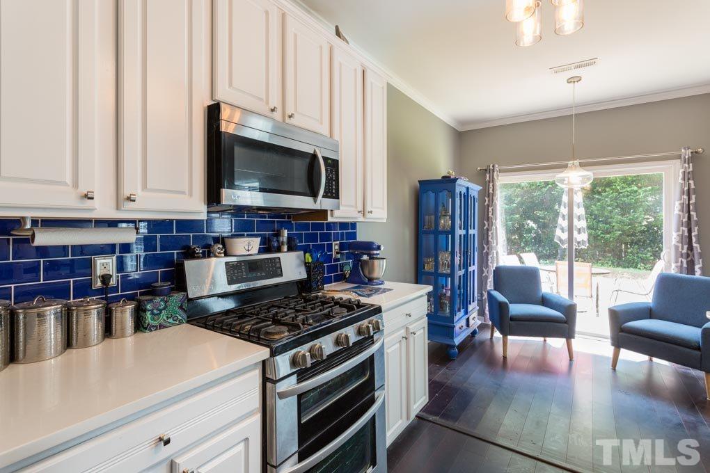 8419 Tie Stone Way Raleigh, NC 27613 - Photo 5 of 30 a kitchen with stainless steel appliances granite countertop a stove top oven a sink dishwasher a dining table and chairs with wooden floor