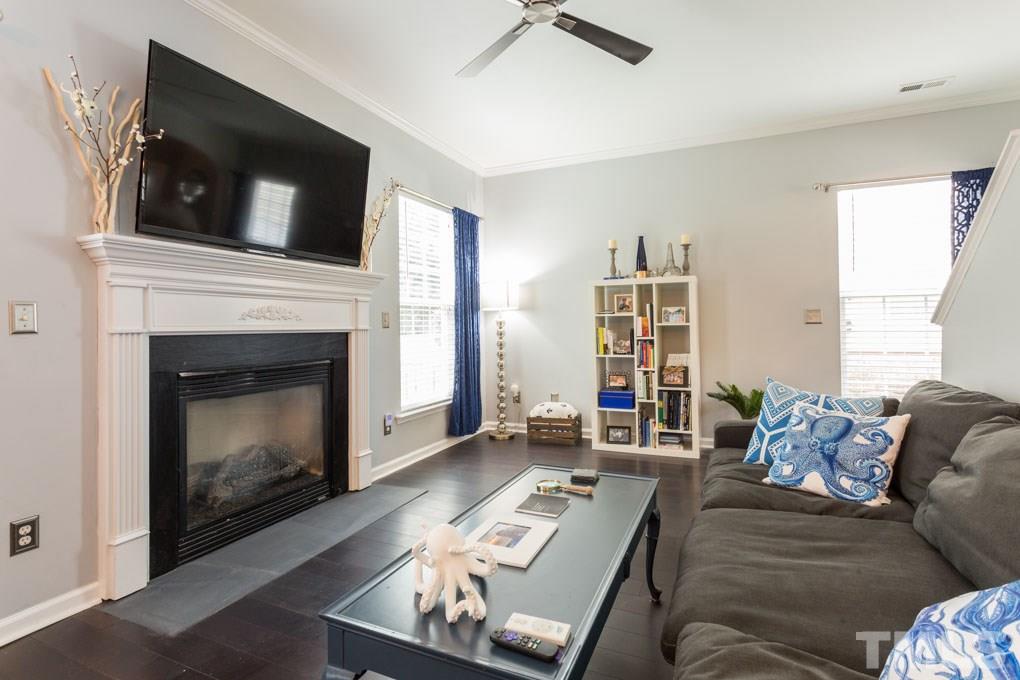 8419 Tie Stone Way Raleigh, NC 27613 - Photo 6 of 30 a living room with furniture a fireplace and a flat screen tv