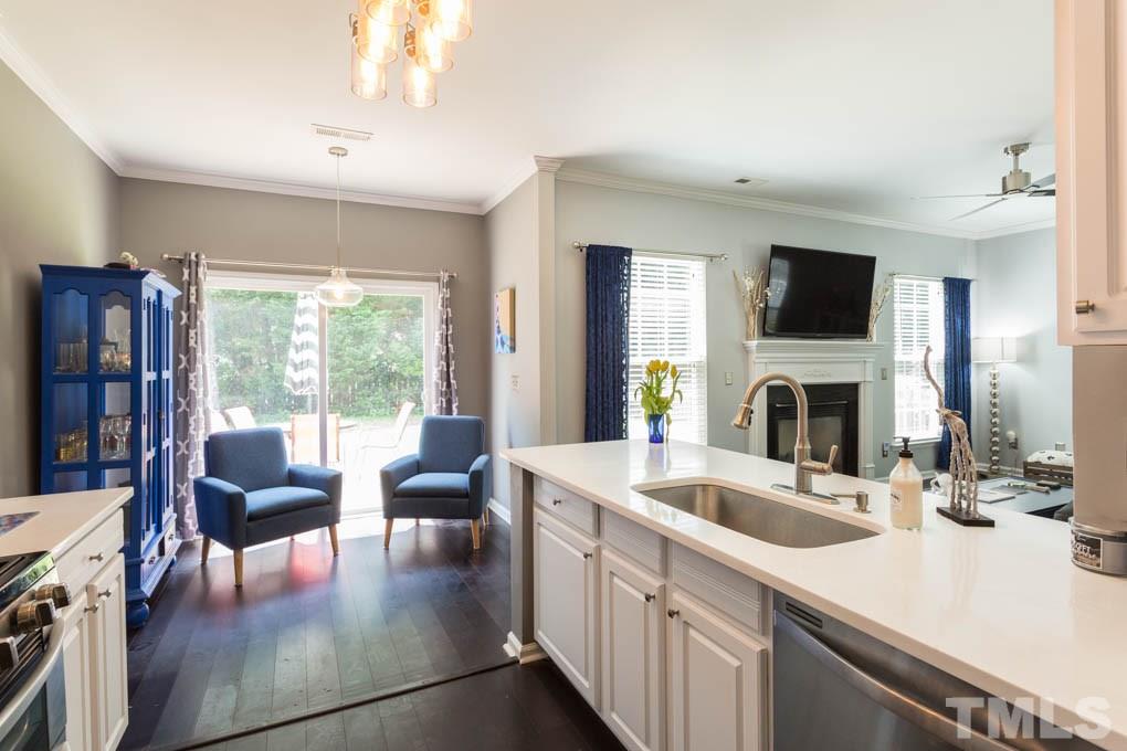 8419 Tie Stone Way Raleigh, NC 27613 - Photo 8 of 30 a kitchen with a sink dishwasher a stove and a dining table with wooden floor
