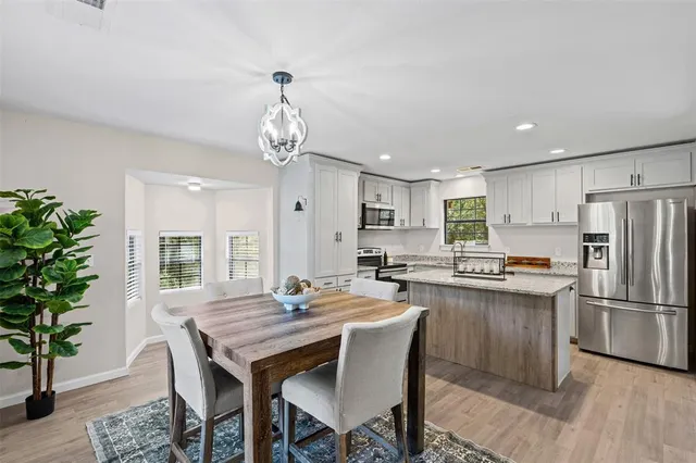 a kitchen with granite countertop a table chairs stove and refrigerator