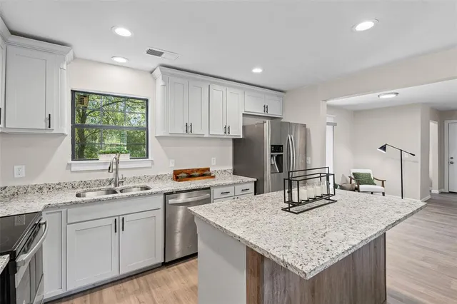 a kitchen with kitchen island granite countertop a sink stove and refrigerator