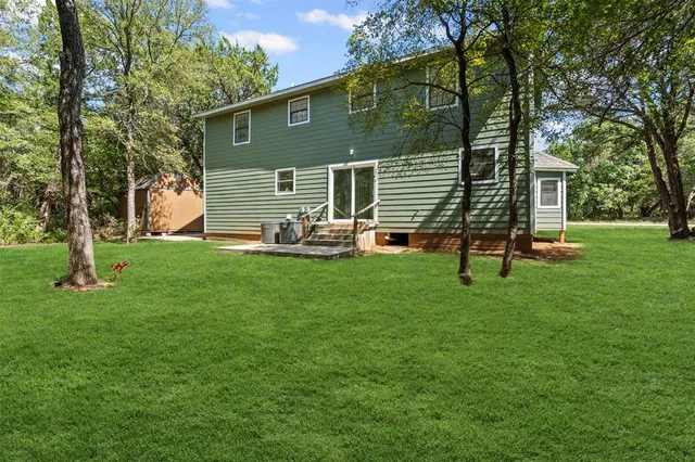 a backyard of a house with potted plants and large tree