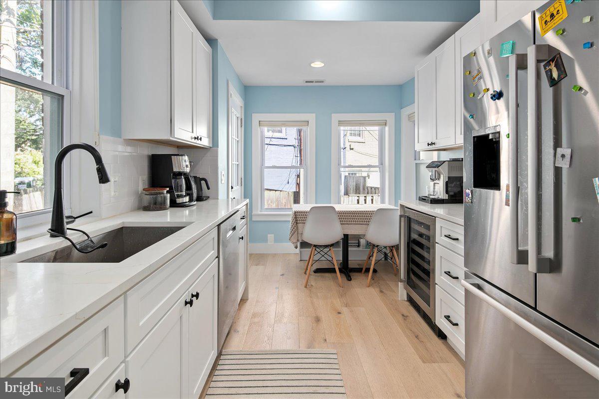 1618 G Street Southeast Washington, DC 20003 - Photo 18 of 53 a kitchen with stainless steel appliances a sink dishwasher a stove a refrigerator and a dining table with wooden floor