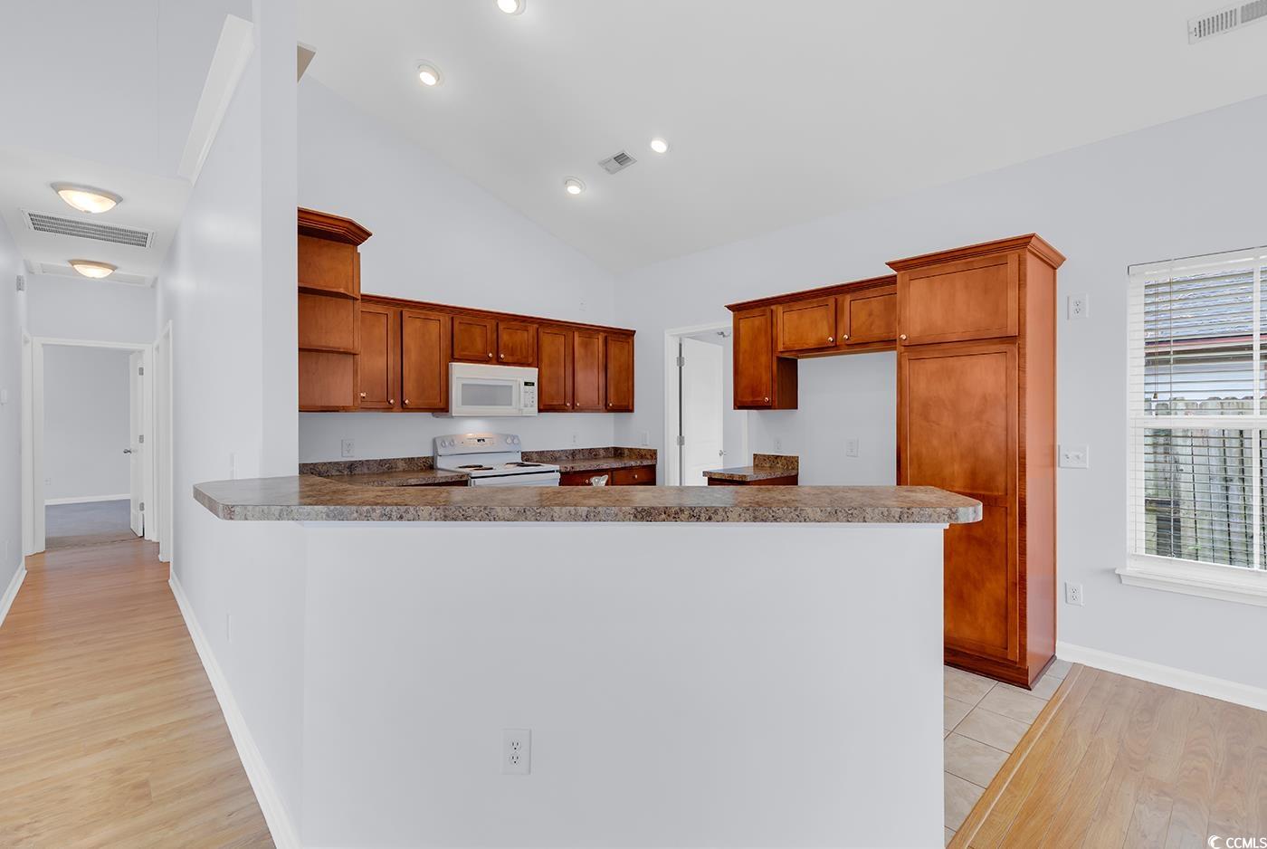 1636 Stuart Square Circle Myrtle Beach, SC 29577 - Photo 12 of 28 Kitchen featuring white appliances, open shelves, light wood-style flooring, a peninsula, and high vaulted ceiling