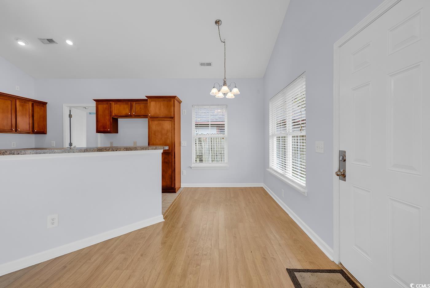1636 Stuart Square Circle Myrtle Beach, SC 29577 - Photo 9 of 28 Kitchen with a chandelier, light wood-style floors, hanging light fixtures, lofted ceiling, and brown cabinets