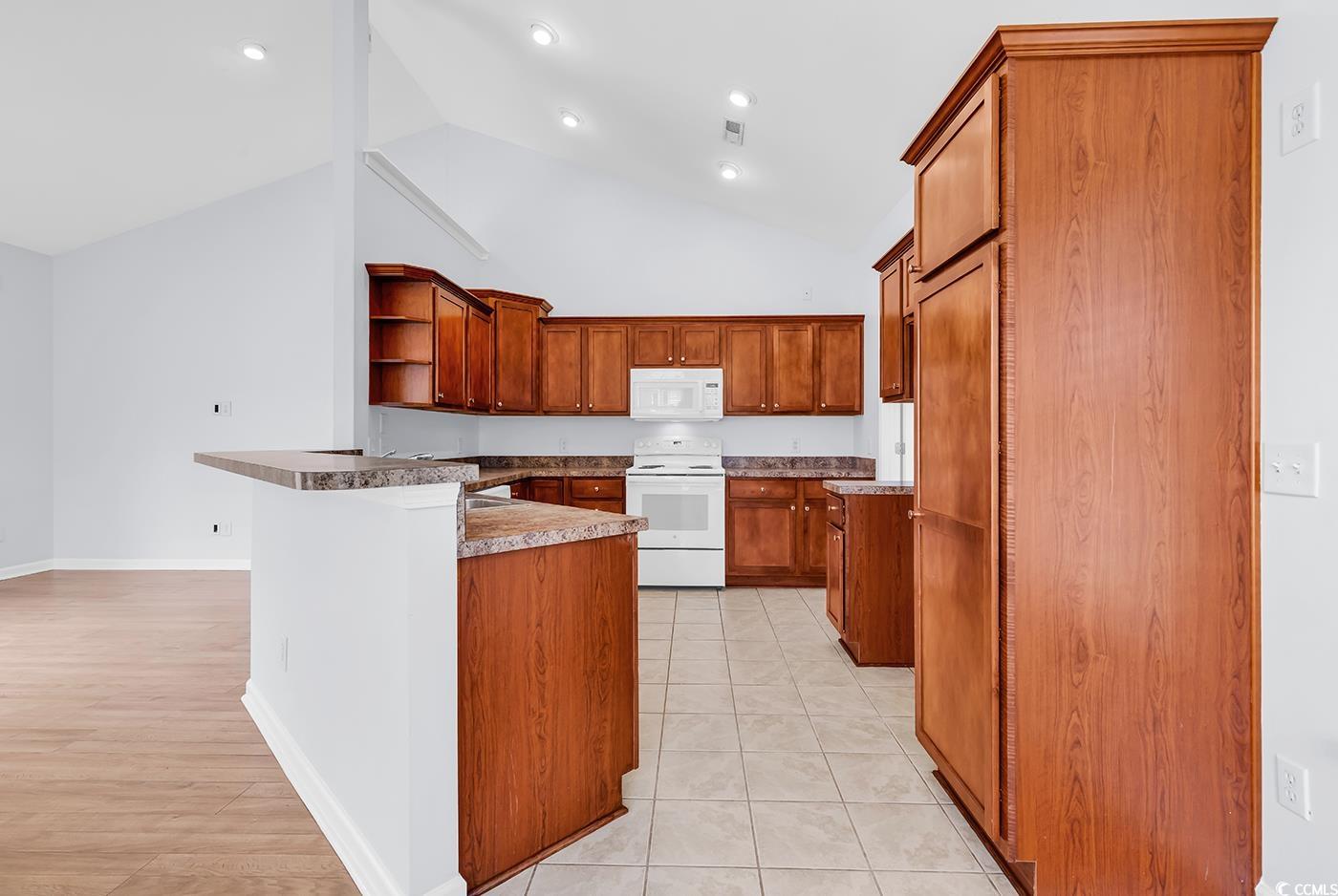 1636 Stuart Square Circle Myrtle Beach, SC 29577 - Photo 10 of 28 Kitchen featuring white appliances, open shelves, brown cabinets, a peninsula, and high vaulted ceiling