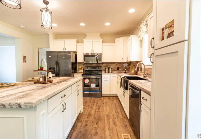 a kitchen with stainless steel appliances kitchen island granite countertop a stove a sink and a refrigerator