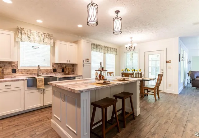 a kitchen with appliances a sink a stove a dining table and chairs