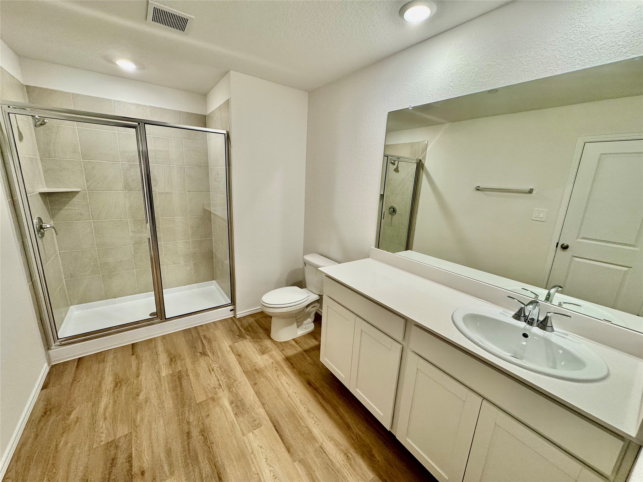 105 Calcite Road, Unit 1 Kyle, TX 78640 - Photo 3 of 7 Bathroom with vanity, a stall shower, light wood-type flooring, and a textured ceiling