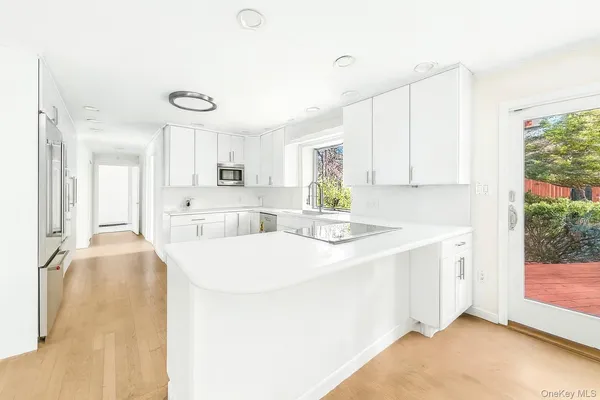 a kitchen with kitchen island a stove a sink a refrigerator and white cabinets with wooden floor