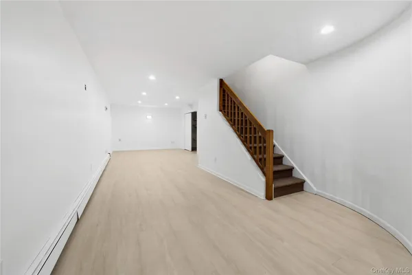 a view of an empty room with wooden floor and stairs