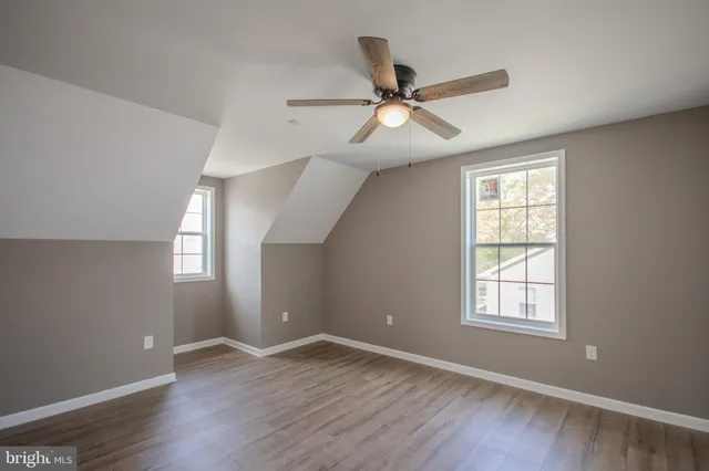 an empty room with wooden floor fan and windows
