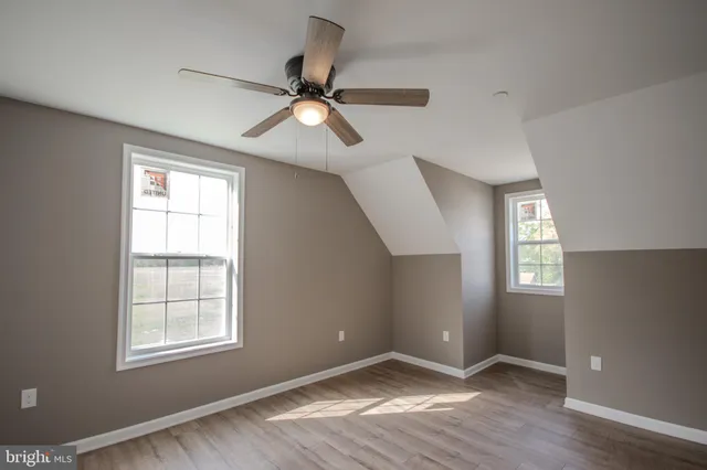 a view of an empty room with wooden floor and window