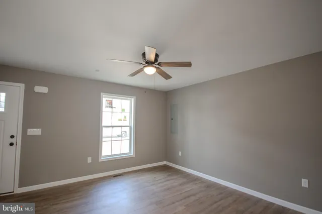 a view of an empty room with wooden floor and a window