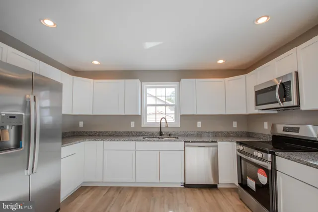 a kitchen with granite countertop a refrigerator sink and white cabinets