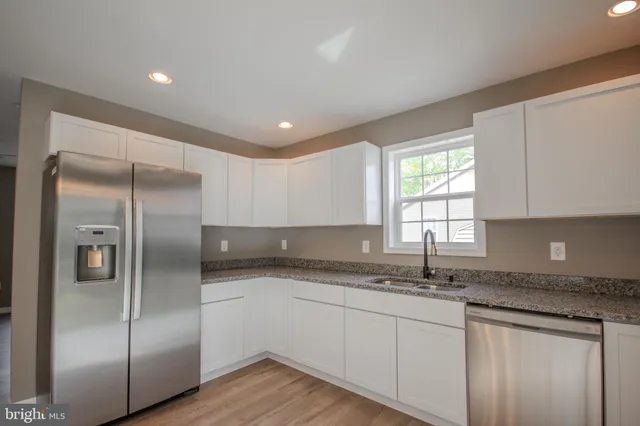 a kitchen with granite countertop stainless steel appliances a sink and a window