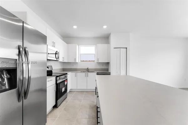 a kitchen with stainless steel appliances granite countertop a refrigerator a stove and a sink