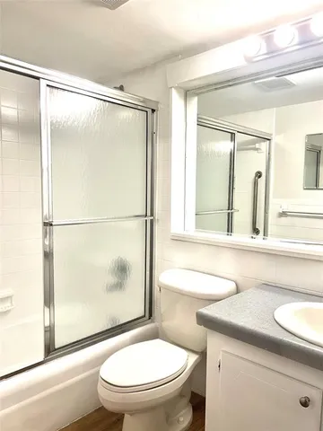 a bathroom with a granite countertop sink toilet a mirror and a shower