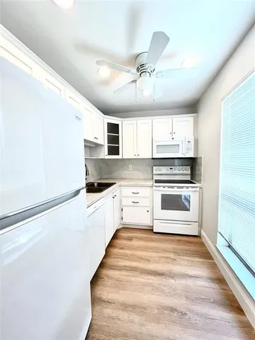 a kitchen with granite countertop a refrigerator and white cabinets