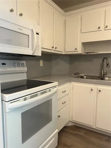 a kitchen with granite countertop white cabinets and white appliances