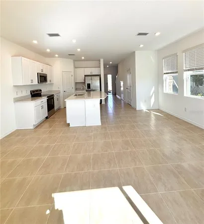 a living room with stainless steel appliances kitchen island granite countertop a sink and cabinets