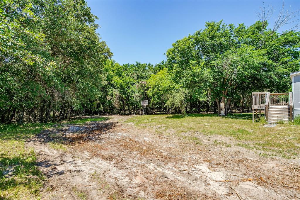178 Valley Lake Lane Springtown, TX 76082 - Photo 28 of 33 Expansive outdoor area featuring mature trees and a wooden deck with railings