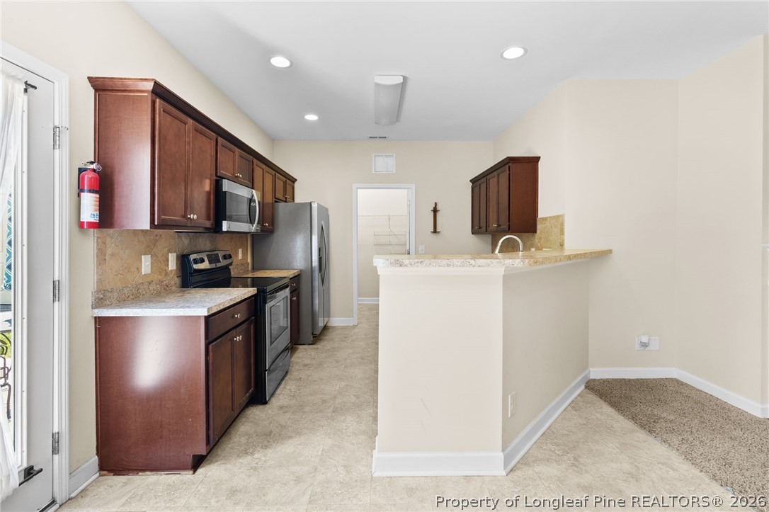 216 Meherrin Loop Raeford, NC 28376 - Photo 11 of 38 a kitchen with stainless steel appliances granite countertop a stove top oven a sink a refrigerator and a microwave