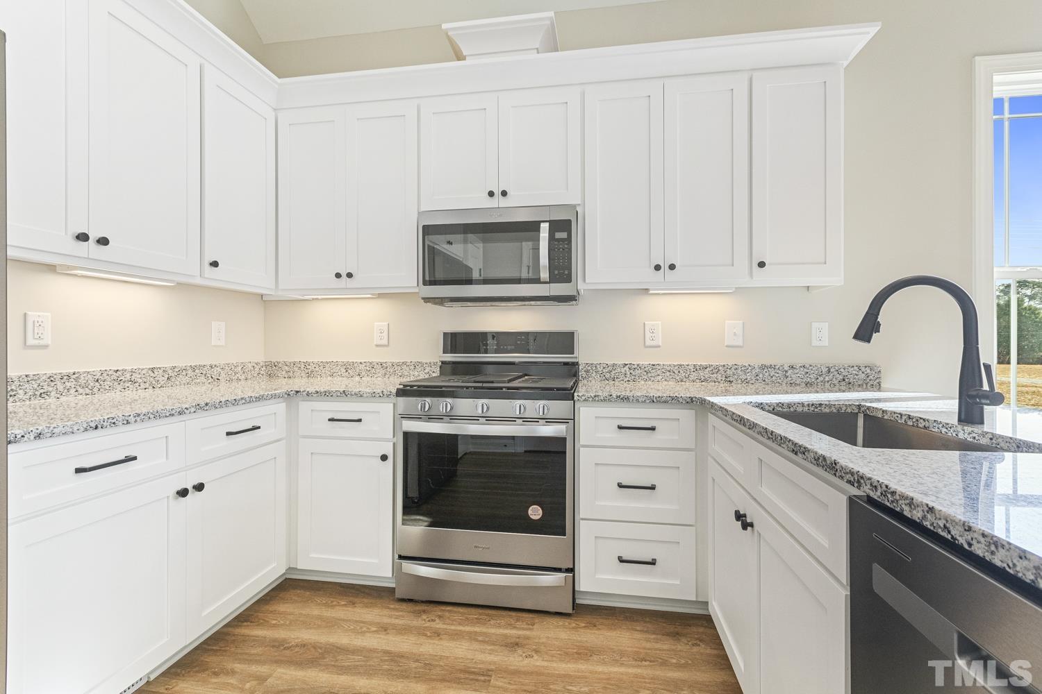 1004 Butler Drive Erwin, NC 28339 - Photo 18 of 38 a kitchen with granite countertop white cabinets and stainless steel appliances
