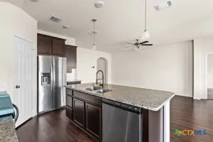 a kitchen with stainless steel appliances granite countertop a sink a refrigerator and wooden floor