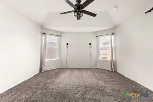 an empty room with windows and ceiling fan