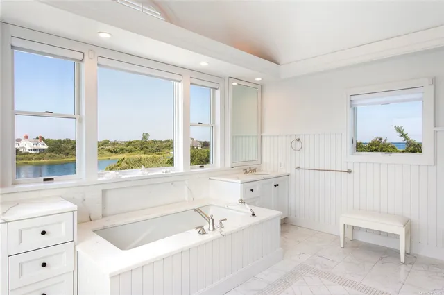 a bathroom with a bathtub a sink and a large window