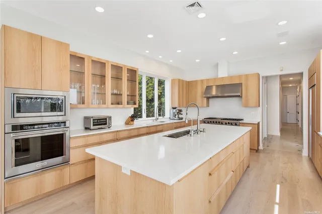 a large kitchen with stainless steel appliances a stove a sink a refrigerator and a oven