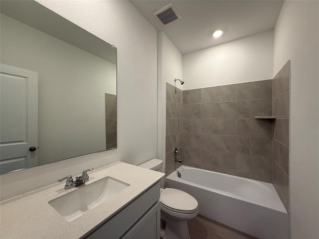 3025 Timber Rdg Drive Anna, TX 75409 - Photo 20 of 23 Bathroom featuring a vanity with an integrated sink, polished chrome fixtures, a full-width mirror, and a tiled tub surround with an integrated shelf