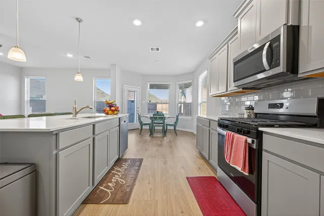 a kitchen with stainless steel appliances granite countertop a sink dishwasher stove and cabinets with wooden floor