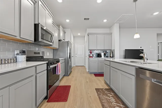 a kitchen with kitchen island granite countertop a sink a counter top space stainless steel appliances and cabinets