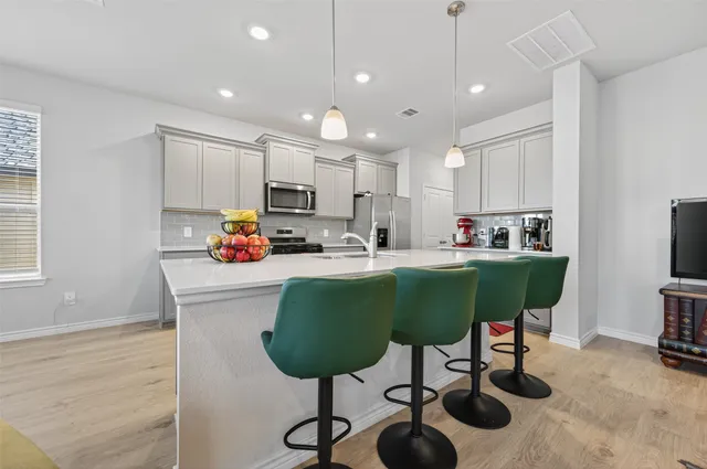 a kitchen with kitchen island stainless steel appliances sink cabinets and a table