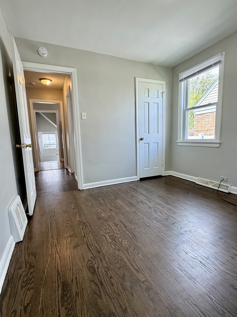 17826 School Street Lansing, IL 60438 - Photo 8 of 23 an empty room with wooden floor and mirror