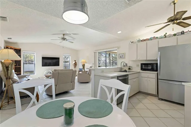 a kitchen with a white appliances a dining table and chairs