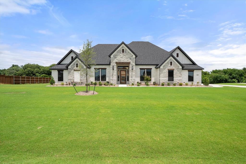 6610 Waggoner Way Midlothian, TX 76065 - Photo 2 of 40 Contemporary single-story residence featuring a stone and board-and-batten facade, dark shingle roofing, and multiple large windows