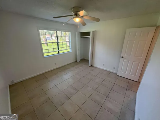 an empty room with windows and fan