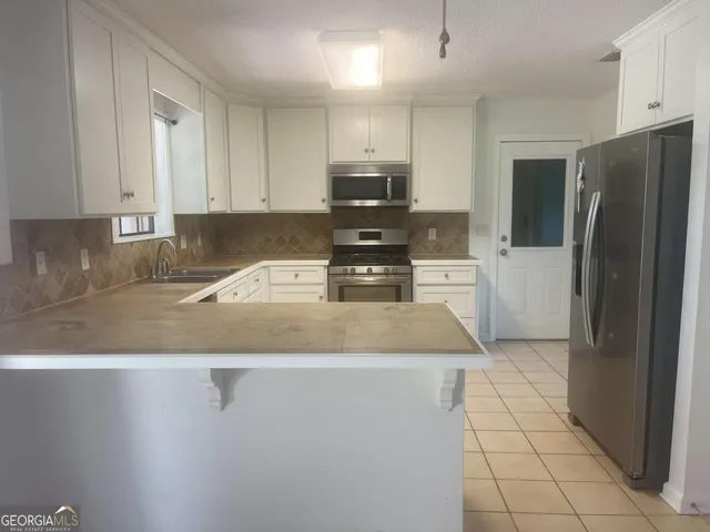 a kitchen with stainless steel appliances granite countertop a refrigerator a stove and a sink with granite countertops