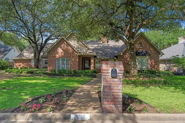 a front view of a house with a garden and tree