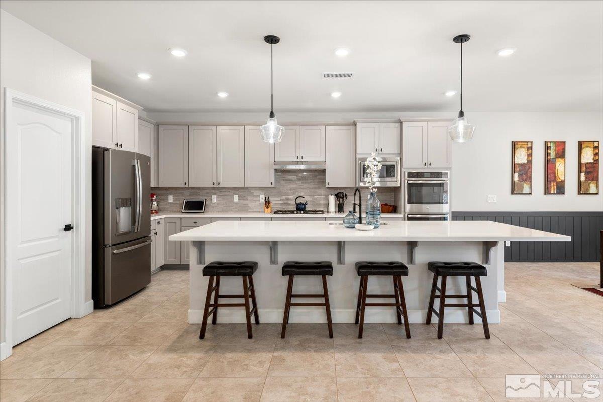 2711 McCauley Ranch Boulevard Reno, NV 89521 - Photo 11 of 40 a kitchen with stainless steel appliances granite countertop a table chairs sink refrigerator and cabinets